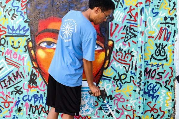 Debris Free Oceans cleanup participant in front of a mural